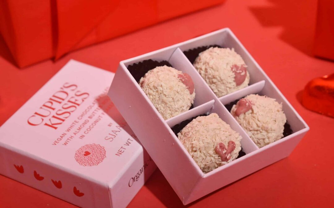 Pink Valentine's gift box filled with coconut-coated sweets beside Cupid's Kisses packaging